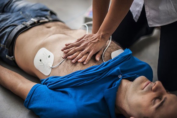 Hands-on CPR with AED pads applied during a training class